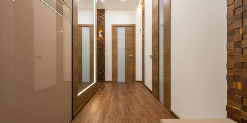 A wide open interior doorway with the door swung fully back against the wall and pale oak flooring running through into a bright hallway.