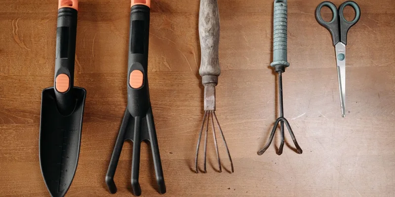 Long handled garden tools with thick moulded grips and a padded kneeler resting on a sunny back patio.