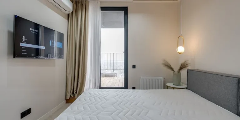 An adjustable bed base with the head section raised, dressed in crisp white bedding in a warm bedroom.