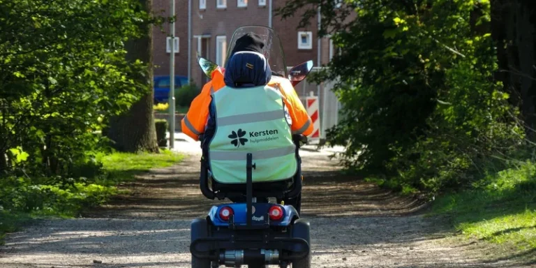 A mobility scooter on a shaded path between grass and trees.