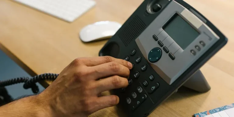 A corded telephone with oversized keys and a side volume slider on a hallway console table.