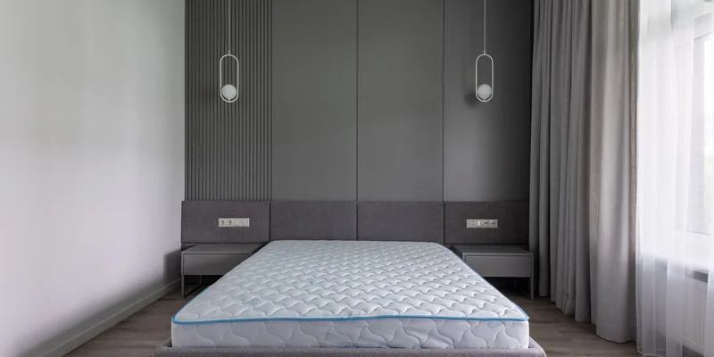 A bed rail standing beside a thick memory foam mattress with its anchor strap running underneath.