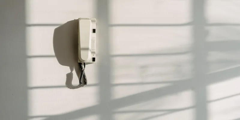 A wireless call button on a nightstand with its plug in receiver in a hallway socket.