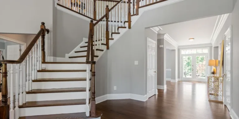 A home entryway with a well lit stair run, a continuous handrail and a low pile mat by the door.