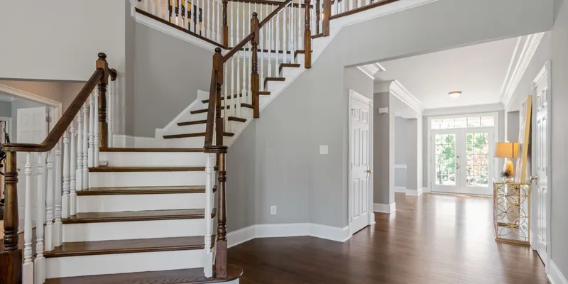 A home entryway with a well lit stair run, a continuous handrail and a low pile mat by the door.