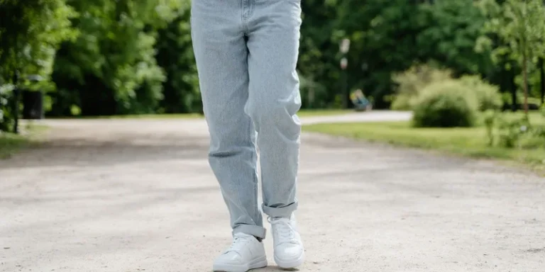 Close-up of a person's legs walking along a paved path.
