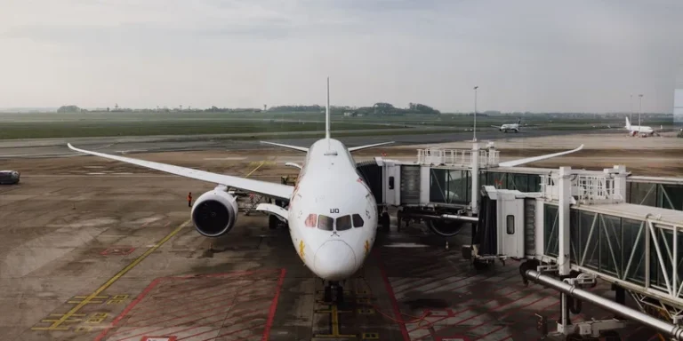 An airplane parked at an airport gate with the jet bridge attached.