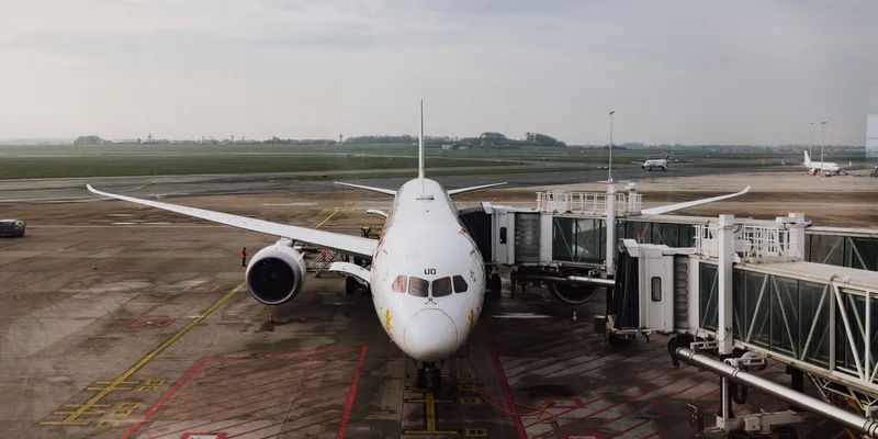 An airplane parked at an airport gate with the jet bridge attached.