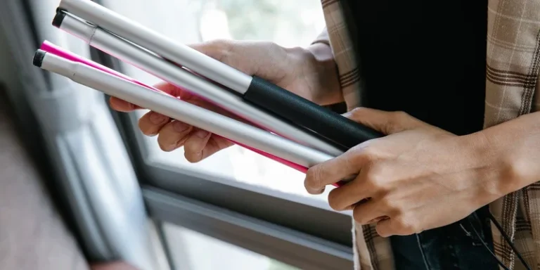 A folding cane collapsed into four sections beside its carry pouch on a console table.