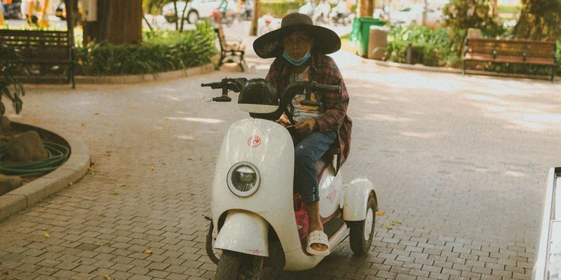 A three-wheel mobility scooter on a park path.