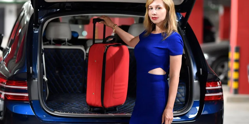 A suitcase being loaded into the trunk of a car.