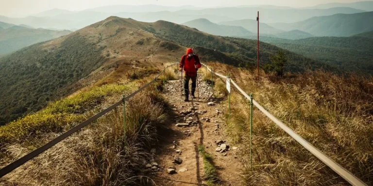 A hiker with a backpack walks a mountain trail.