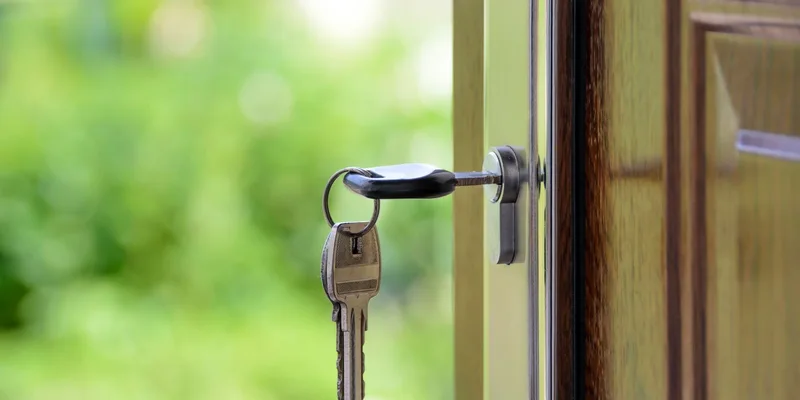 A key fitted with a moulded turner grip in a front door lock below a lever handle.
