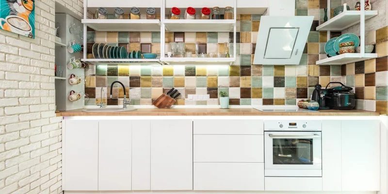 A kitchen with everyday items stored at waist height, a clear counter and a kettle near the sink.