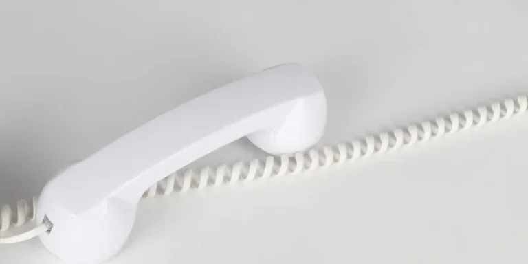 A corded landline phone on a hallway table with its cord neatly coiled.