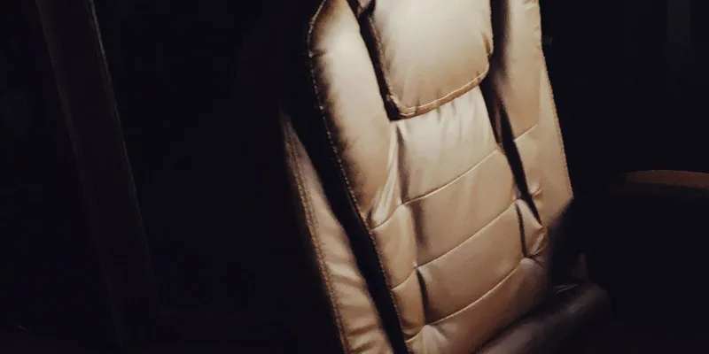 A leather upholstered lift recliner in a warm living room with light from a side window.