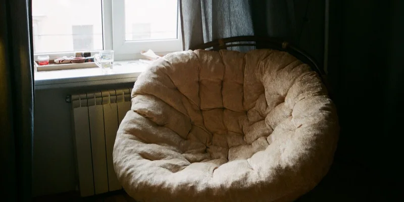 A spring assisted lift cushion sitting on the seat of an armchair in a living room.