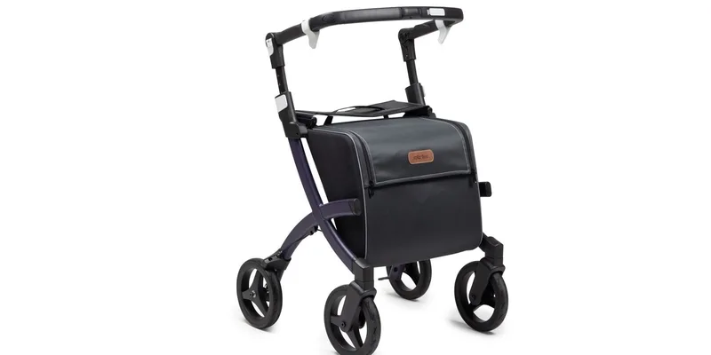 A slim lightweight rollator with a narrow frame standing in a sunlit hallway.