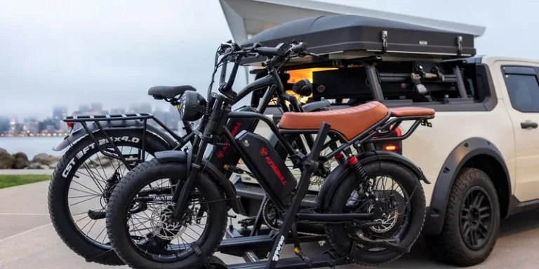 Two bikes strapped to a carrier rack on the back of a vehicle.