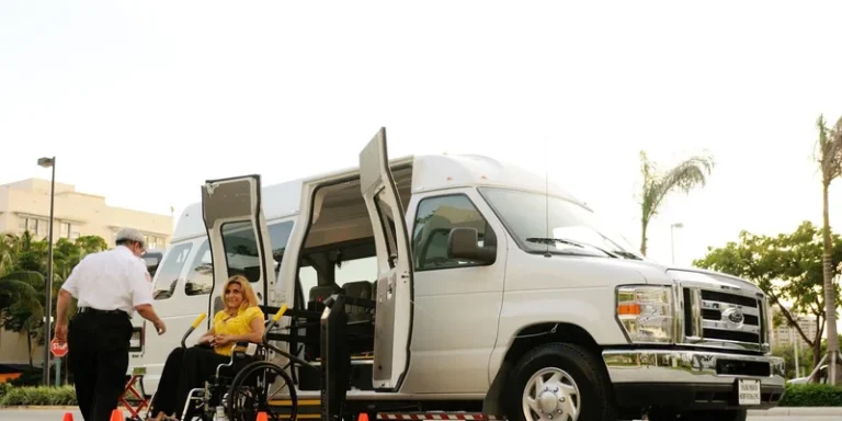 A seated passenger boards a van using a powered lift.