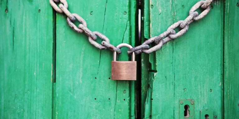 A heavy chain and padlock securing a wooden door.