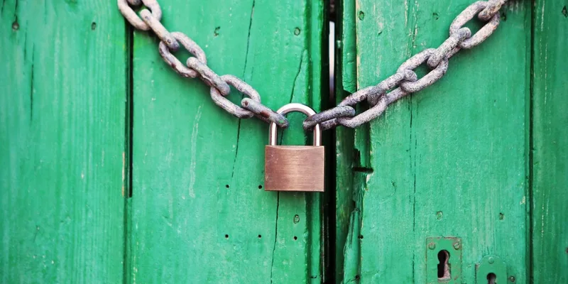 A heavy chain and padlock securing a wooden door.