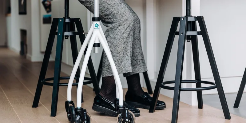 A narrow rollator passing through a tight interior doorway in an apartment.