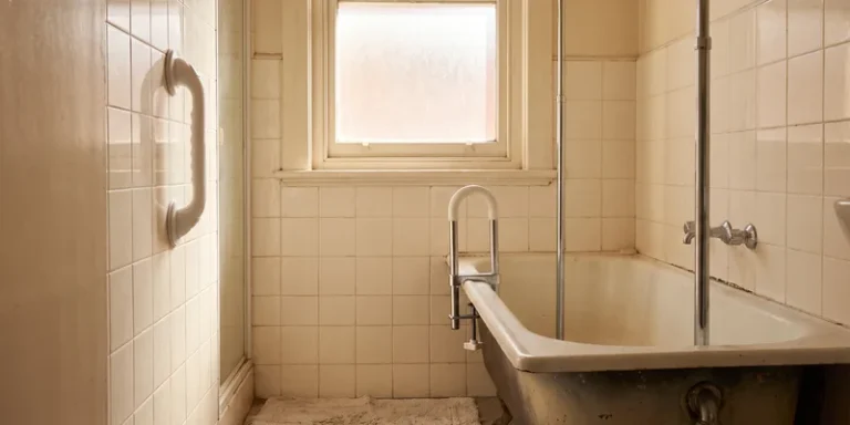 A suction grab bar, a clamp on tub rail and a tension pole grouped in a rental bathroom.