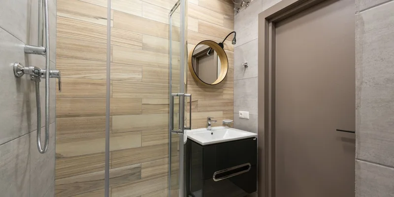 A compact corner shower stool tucked into the corner of a small tiled shower.