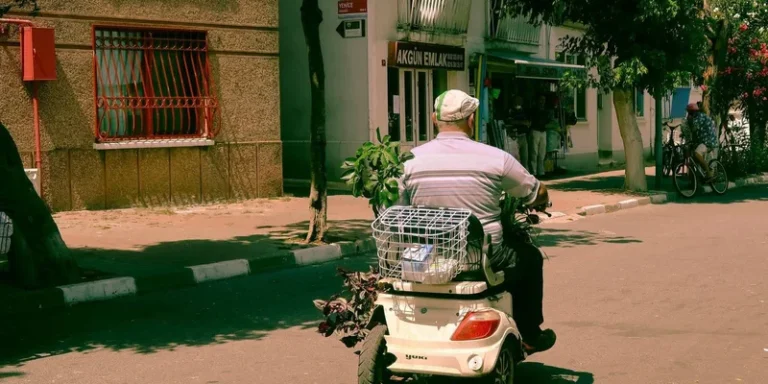 A senior man rides a mobility scooter with a shopping basket.